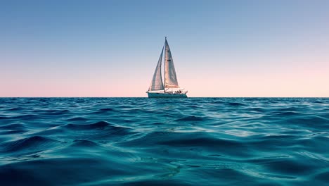 Low-angle-sea-level-view-of-small-yacht-boat-sailing-in-calm-open-sea-at-sunset