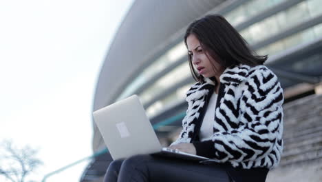 upset young businesswoman typing on laptop and rubbing forehead