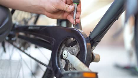 Caucasian-male-mechanic-hand-puts-screw-on-frame-of-bicycle-and-uses-screwdriver-to-tighten,-close-up-static