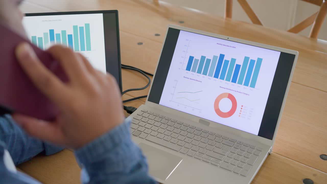 Man holding purple smartphone and pointing across laptop bars, answering call and explaining data