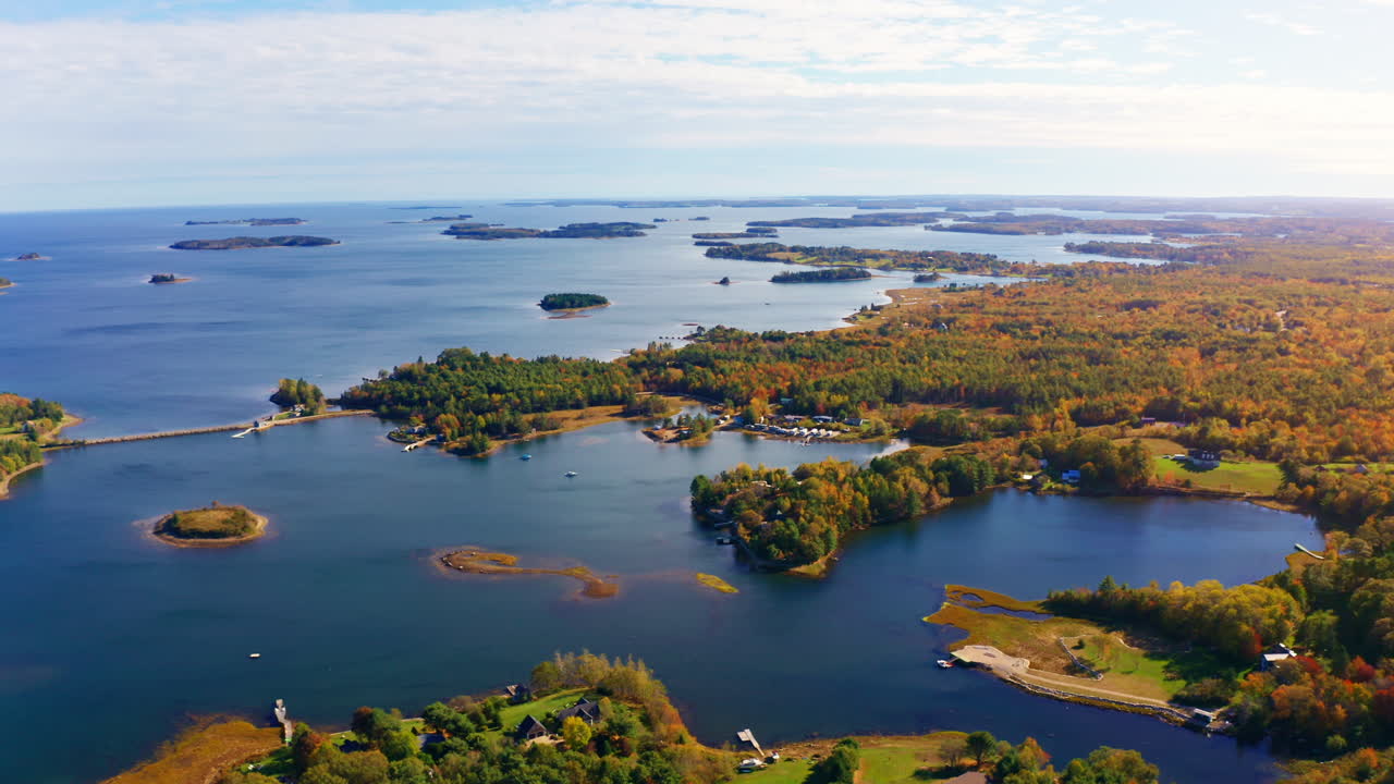 Aerial drone shot over the coastline of Oak Island, Nova Scotia, Canada.
High view of the sea, autumn colorful trees foliage. Picturesque landscape. Fall vibrant colors.