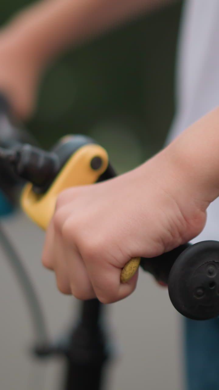 primer plano de la mano de un niño agarrando la palanca de freno en el manillar de una bicicleta