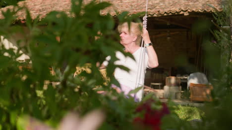 Push-shot-reveals-woman-enjoying-solitude-of-garden-swing-on-summers-morning