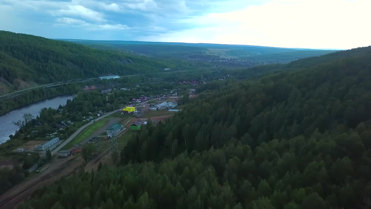 vista aérea de una aldea ubicada en un valle con bosques circundantes y un río