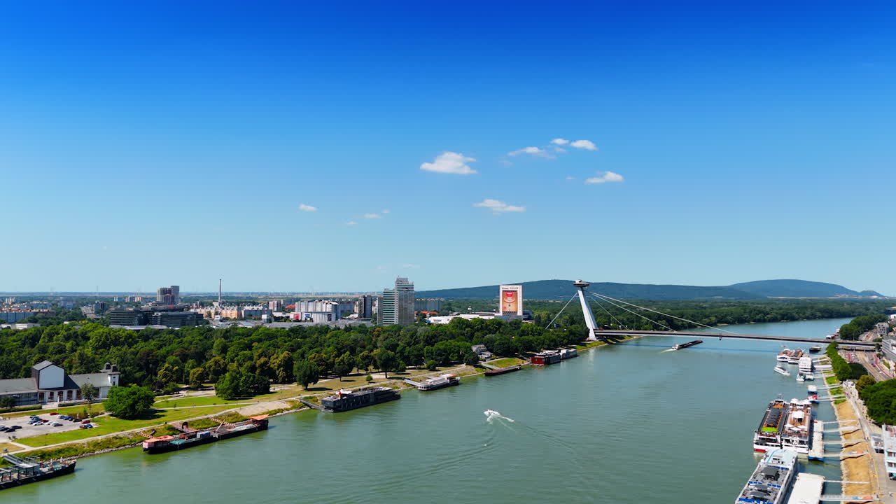 Bratislava's Danube view. Overlooking the Danube River, Bratislava showcases modern architecture and lush greenery on a sunny day