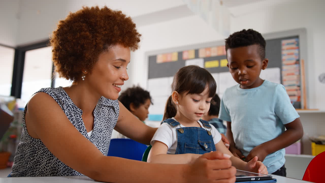 maestra con alumnos de escuelas primarias multiculturales que usan tabletas digitales en la escuela