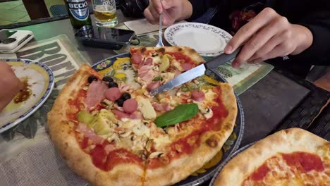 person slicing and serving pizza at a table