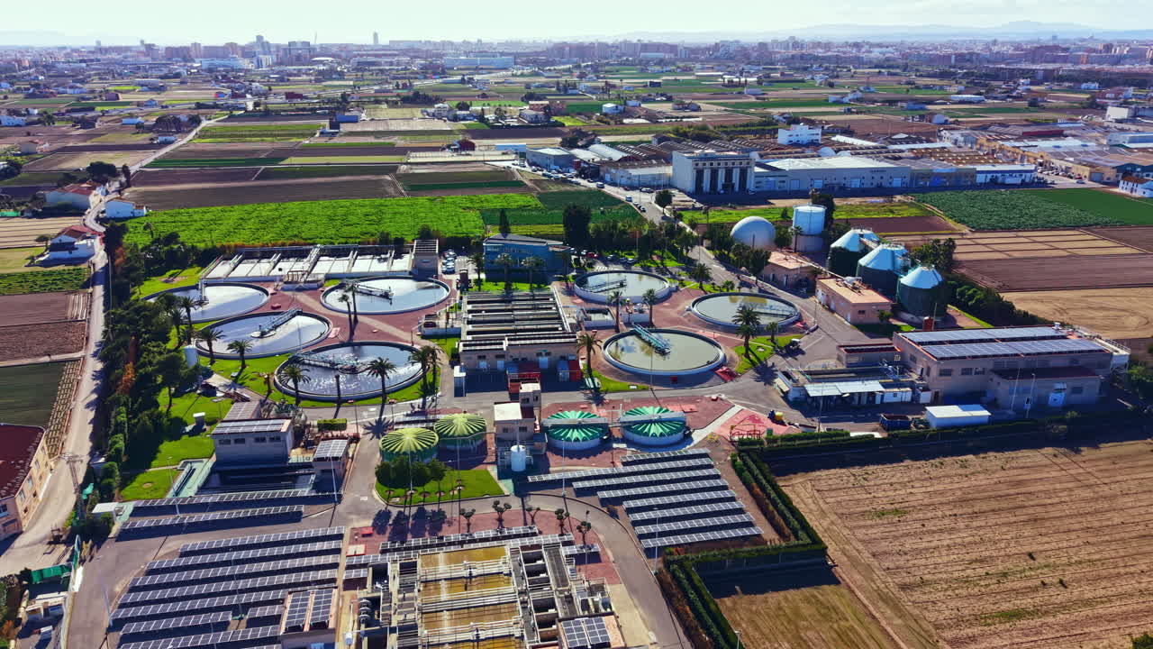 Water treatment facility in a rural area with circular tanks and green fields in the background during daylight hours