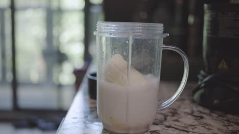 Man-Pouring-Fresh-Milk-Into-A-Cup-With-A-Banana