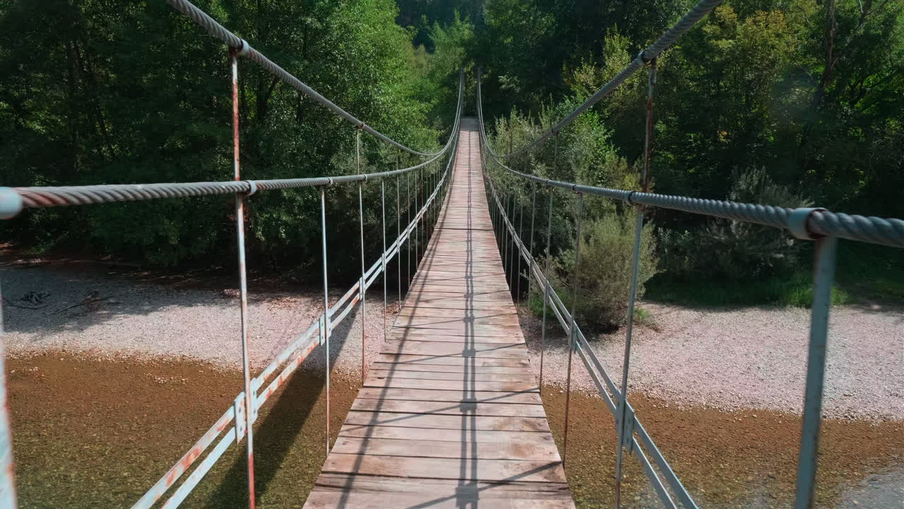 Picturesque Suspension Bridge Over a Calm River in a Lush Forest