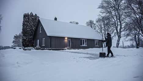 一名男子在寒冷的日子里在乡村小屋里铲雪 - - 时间流逝