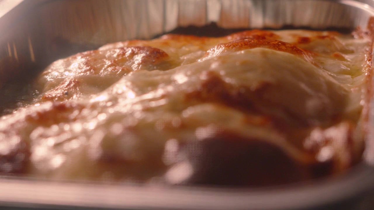 Deliziose patate gratin dauphinoise che cuociono fino a diventare dorate e croccanti all'interno di un forno. Fette di patate stratificate con panna bollente, aglio e formaggio fuso. Perfetto per documentari culinari