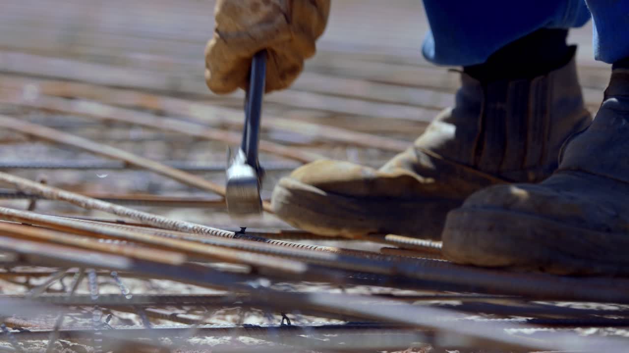 Construction worker ties rebar together with wire to create a reinforcing grid for the concrete foundation