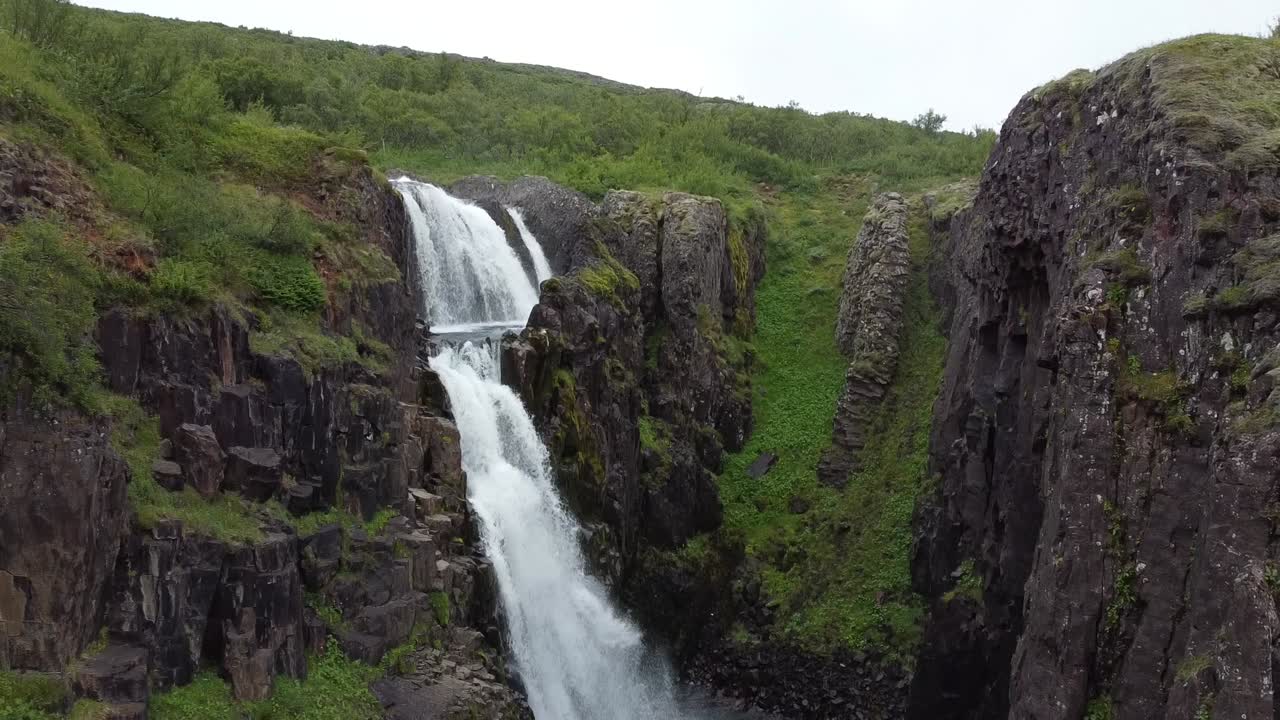 toma aérea ascendente de la caída de la cascada de glymur en el idílico paisaje de islandia