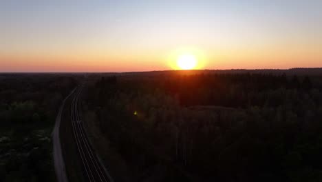 sunset over forest landscape with railroad tracks leading into the distance