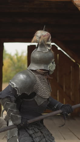 evil knight with spear walks through rainy courtyard to medieval castle for battle. mystical creature attacks human settlement closeup on blurred background