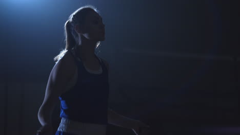 woman boxer jumping on skipping rope in the boxing hall with a ring