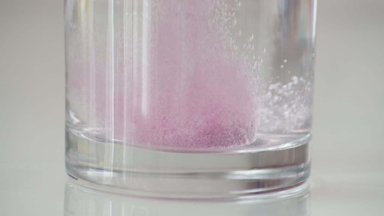 cámara lenta rosa vitamina c efervescente cae y se disuelve en agua