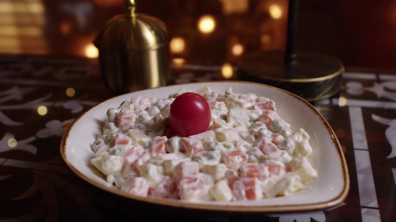 Plate of creamy diced vegetable salad with tomato garnish on a decorated table indoors