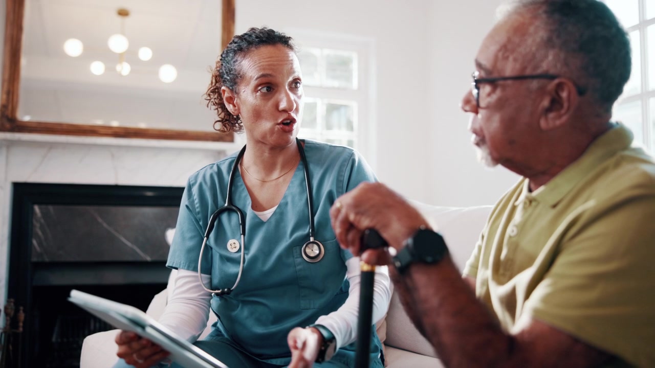 Female Nurse Discussing Medical Information With Senior Patient at Home