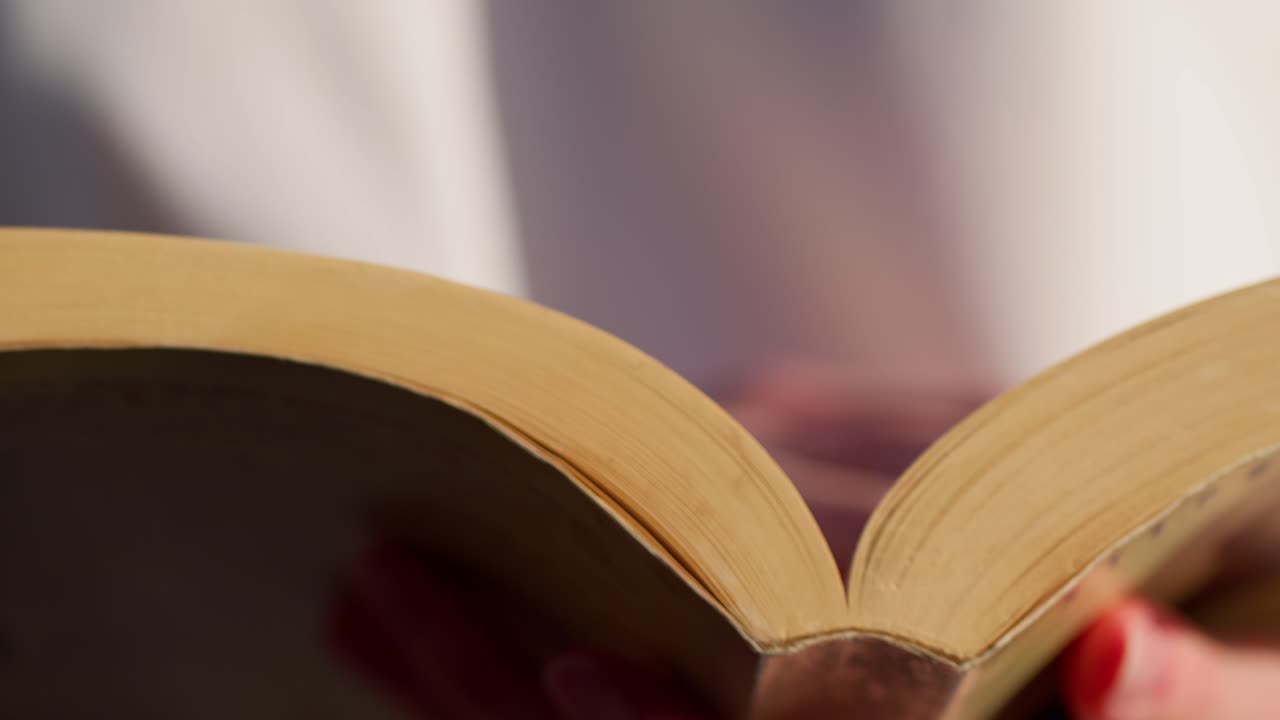 fotografía macro frontal de las manos de una niña volviendo una página mientras el viento sacude las páginas junto al océano en sicilia, italia (sicilia, italia)