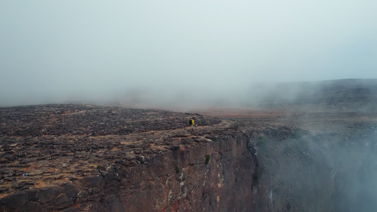 hombre caminando por una montaña en un clima brumoso