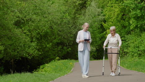 young woman assisting elderly woman in park