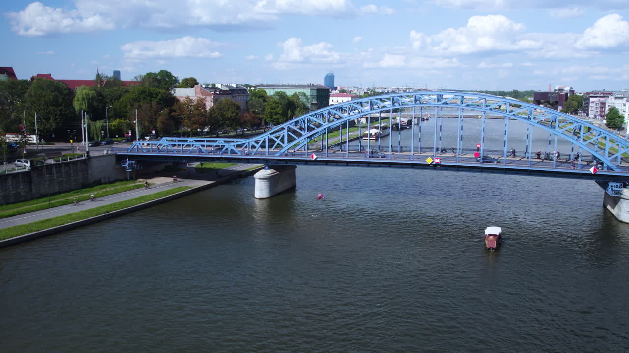 Ripresa aerea all'indietro del fiume Vistola e di auto che attraversano il ponte blu a Cracovia, Polonia