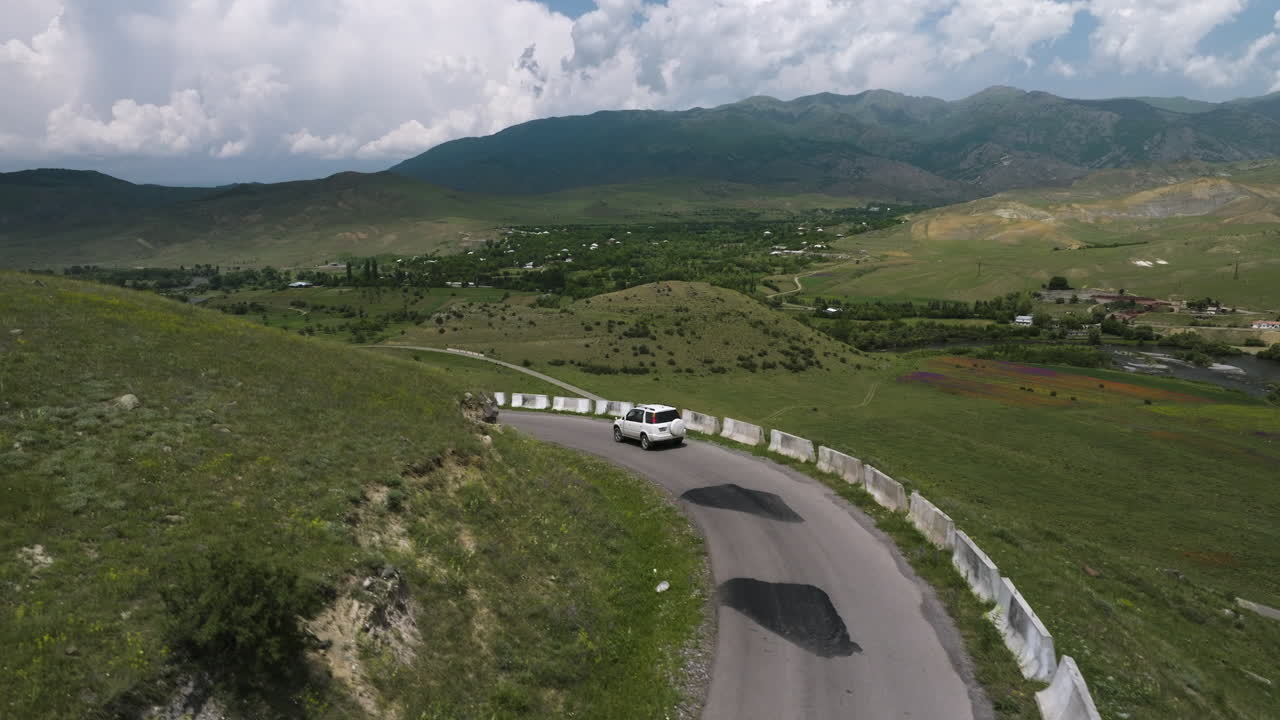 coche blanco solitario conduciendo a lo largo de la carretera de montaña del acantilado con barrera de hormigón fuera del distrito de aspindza en georgia
