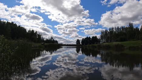 vibrant scenic blue lake water mirror reflection of bright clouds and trees in sky