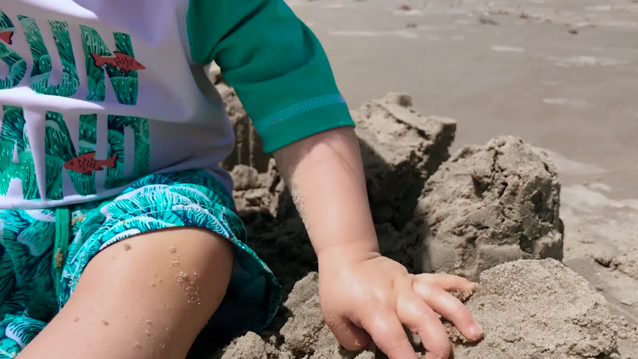 Toddler playing with sand between fingers.