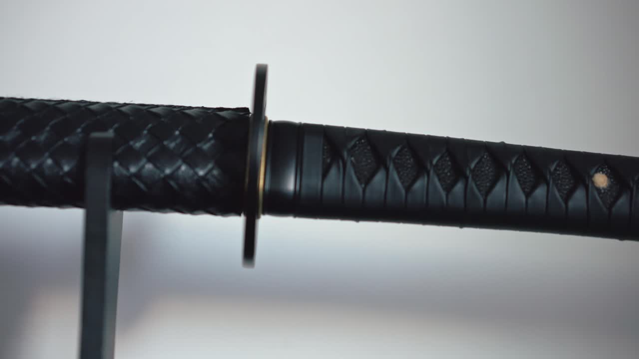 una katana negra magistralmente hecha a mano con una vaina escamosa exhibida en un pedestal en casa