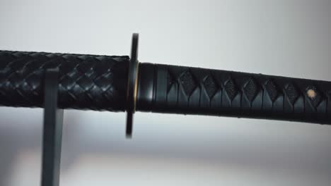 A-masterfully-crafted-black-katana-with-a-scaly-scabbard-displayed-on-a-plinth-at-home