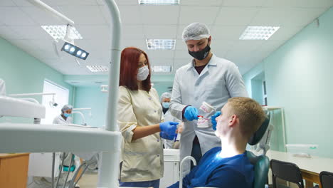 tall male medic student shows the patient teeth model. future dentist teaching a patient to clean teeth correctly.