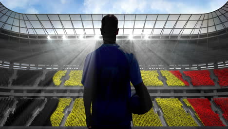 animation of rear view of football player holding ball over belgian flag in sports stadium