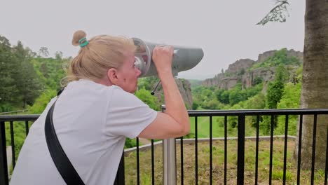 female looks through observation telescope at scenic lookout point