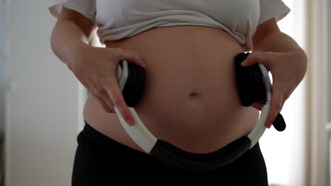 pregnant woman putting headphones on her tummy for baby to listen to music