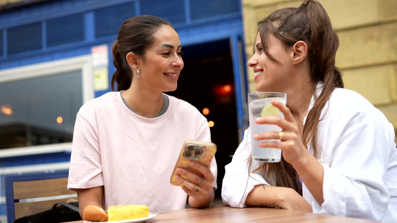 Two women looking at a smartphone in a cafe