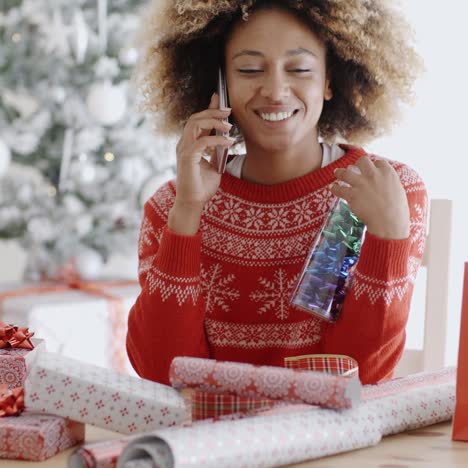 Woman-chatting-on-a-mobile-as-she-wraps-gifts