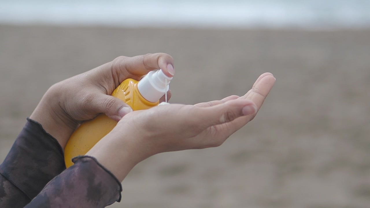 Close-up of Hands Spraying Sunscreen onto Palm
