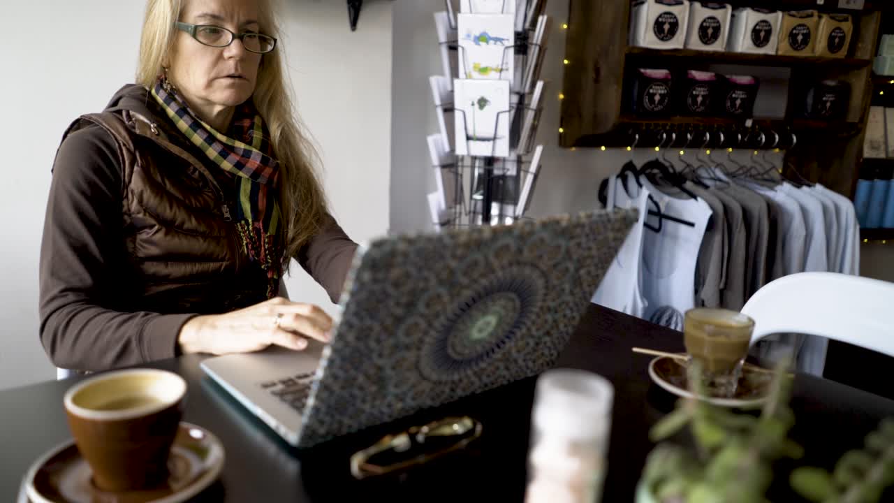 mujer trabajando en una computadora portátil en un café