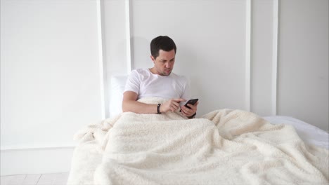 hombre usando teléfono inteligente en la cama