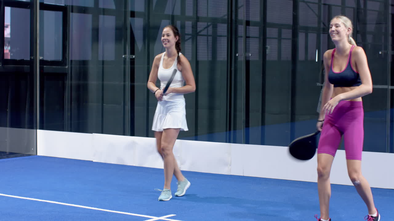Women playing padel tennis on blue indoor court, focusing on game