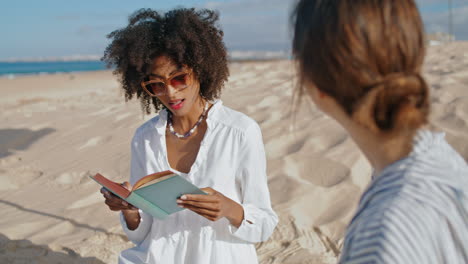 stijlvol afro-amerikaans meisje dat boek leest op het zomerstrand verticaal georiënteerd.