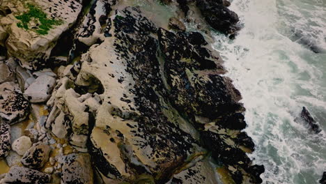 super slow motion atlantic ocean waves hitting rocks, revealing a beach