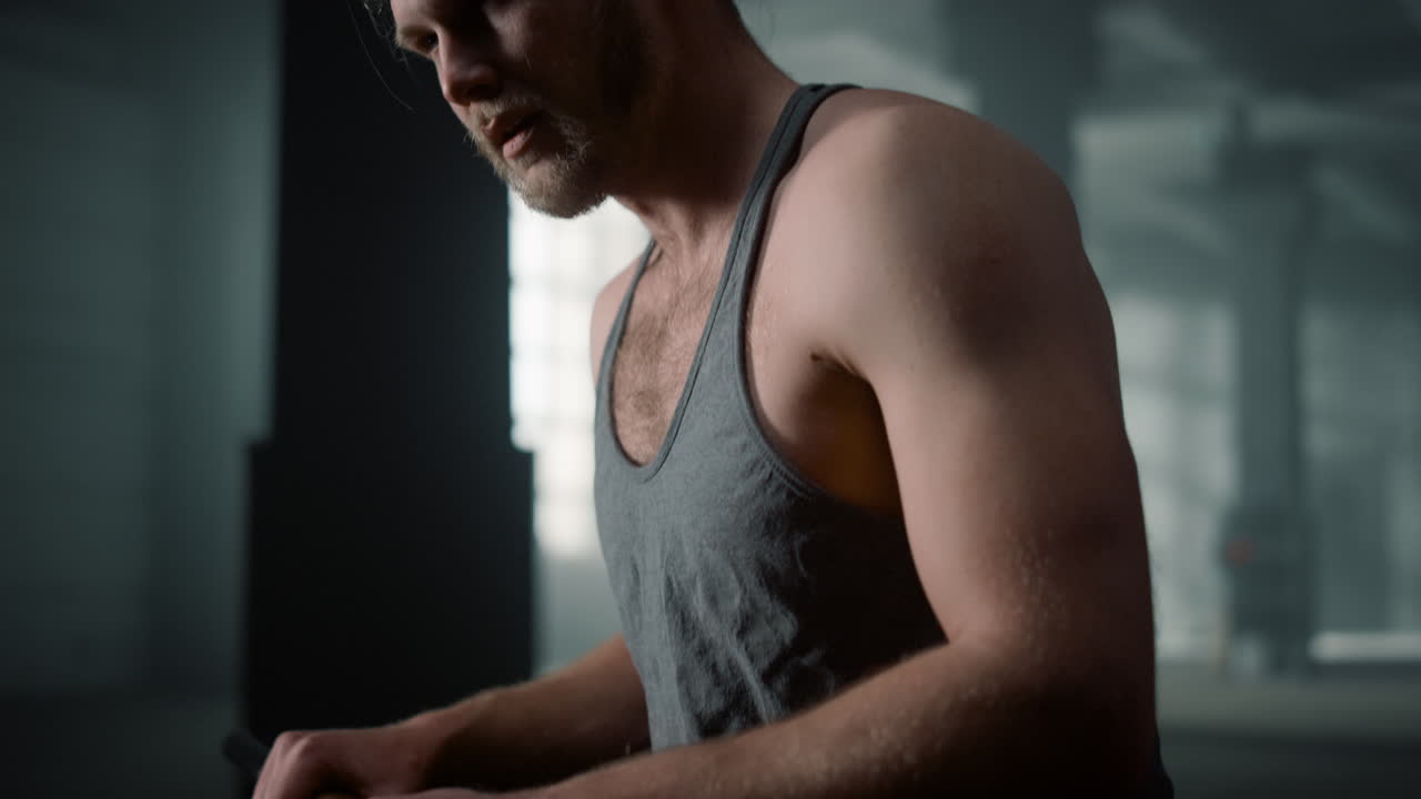 체육관에서 카메라에 포즈를 취하는 운동 선수. 망치와 함께 고무 타이어에 앉아있는 운동 선수