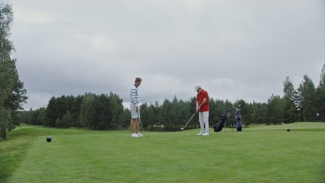 two men playing golf on a cloudy day