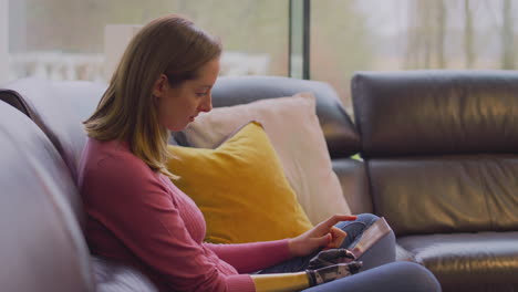 mujer con brazo y mano protésicos en casa usando una tableta digital