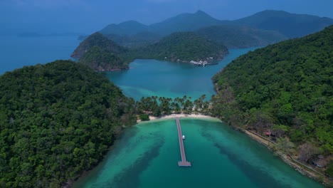 koh chang's ko ngam idyllic landscape, featuring lush greenery, a pristine beach, and a tranquil pier extending into the turquoise waters. unbelievable aerial view flight panorama overview drone