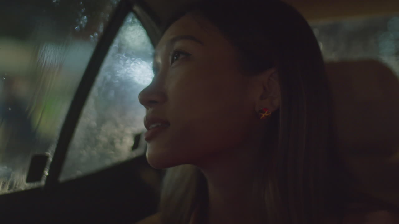 Asian Woman Speaking on Phone in Car at Night